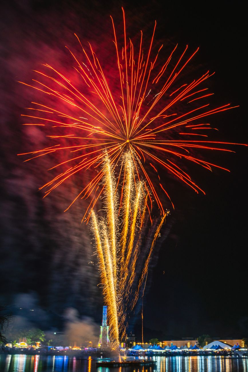 fireworks over the water at night with a boat in the background